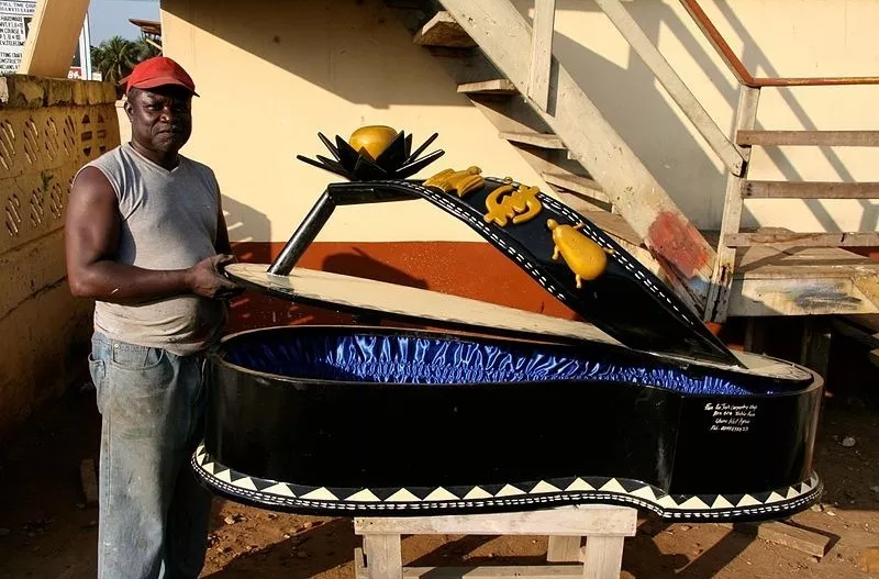 Un artigiano ghanese posa con la sua bara
